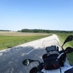 Cockpit einer BMW R 1200 GS mit Blick auf eine kurvige Landstraße durch grüne Felder und Wälder.