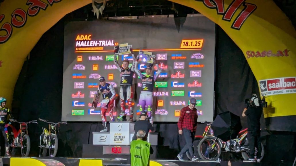 Siegerehrung beim ADAC HALLEN-TRIAL am 18.1.25. Zwei Motorrad-Trial-Fahrer feiern auf dem Podest.