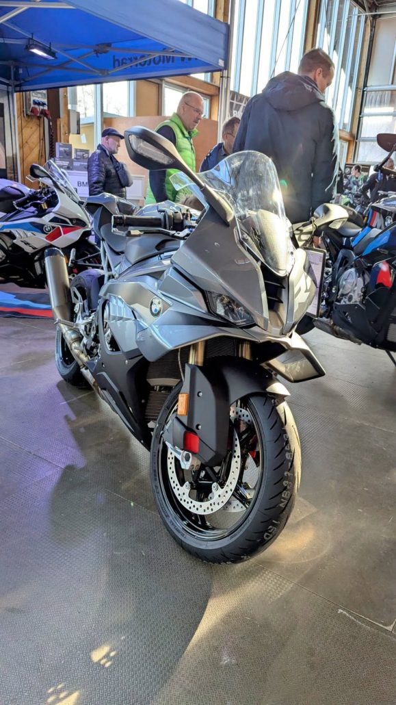 Graue BMW S 1000 RR Supersport-Maschine mit Vollverkleidung und schwarzem Kunststoff, ausgestellt in einer Halle.