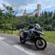 Grau-schwarzes BMW R 1200 GS Motorrad am Straßenrand vor einem bewaldeten Hügel mit einer Burg.