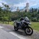 Grau-schwarzes BMW R 1200 GS Motorrad am Straßenrand vor einem bewaldeten Hügel mit einer Burg.