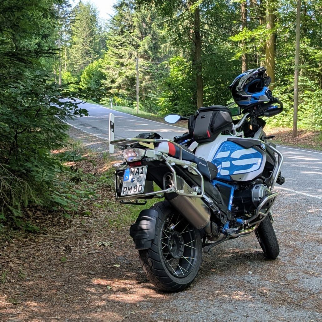BMW R 1200 GS Adventure Motorrad in Blau/Weiß, steht auf einem Waldweg