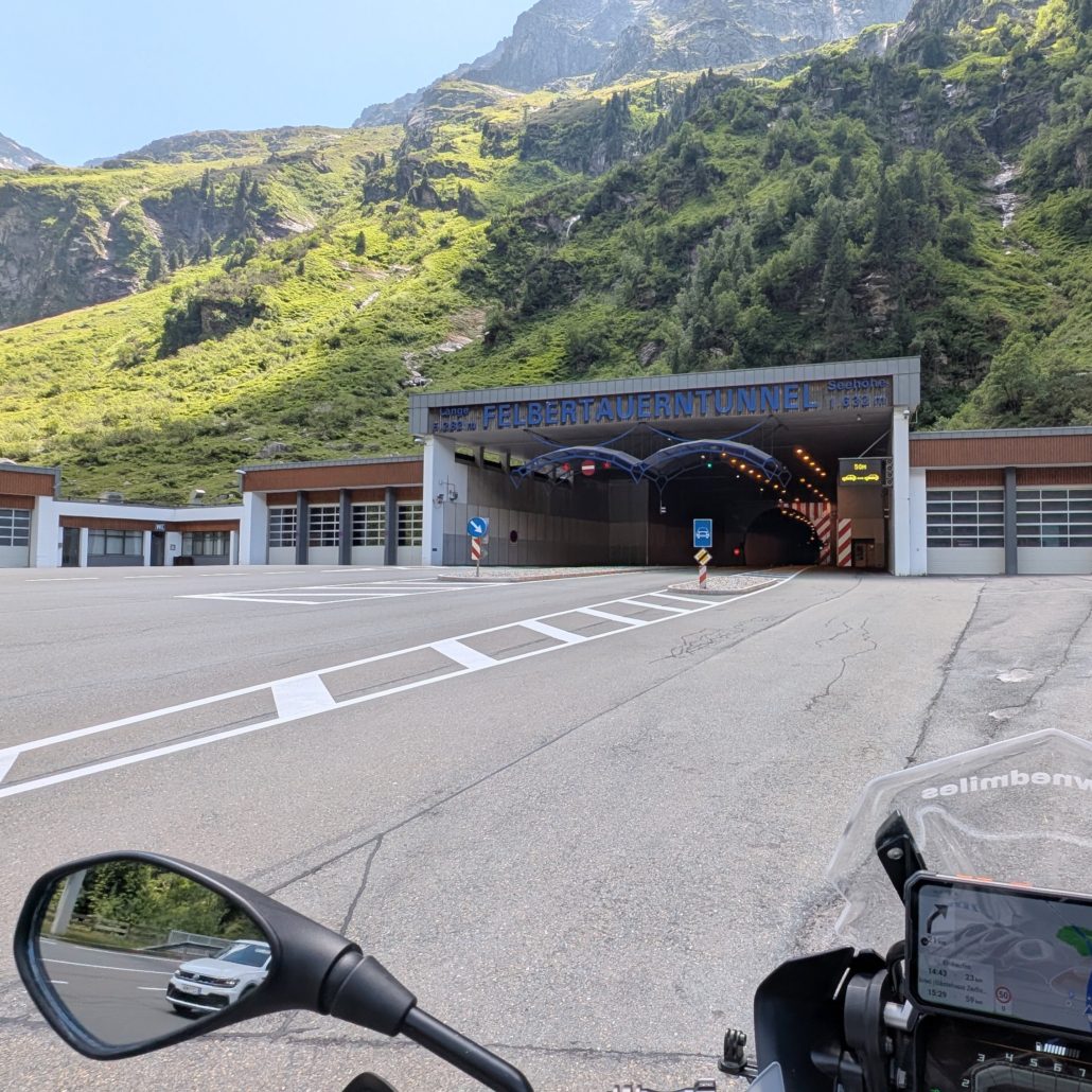 Eingang zum Felbertauerntunnel in den Alpen, gesehen von einem Motorrad aus. Das Tunnelportal zeigt "FELBERTAUERNTUNNEL".