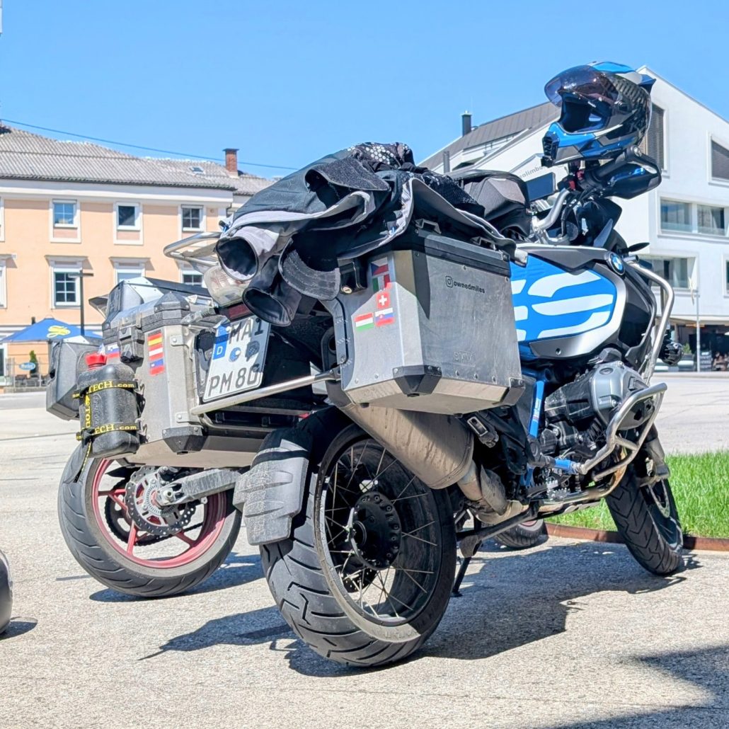 Beladene, weiß-blaue BMW R1250 GS Reiseenduro mit Alu-Koffern und internationalen Aufklebern.