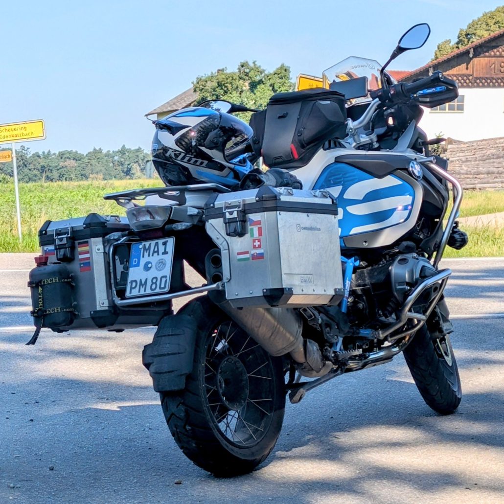 Blau-weiße BMW Reiseenduro mit Aluminium-Koffern, Tankrucksack und Helm.