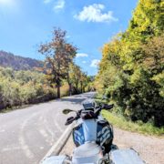 Motorrad auf einer ländlichen Straße im Herbst; der Himmel ist blau mit weißen Wolken.