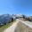 Blick über die Rossfeld Panoramastraße auf verschneite Alpengipfel unter strahlend blauem Himmel.