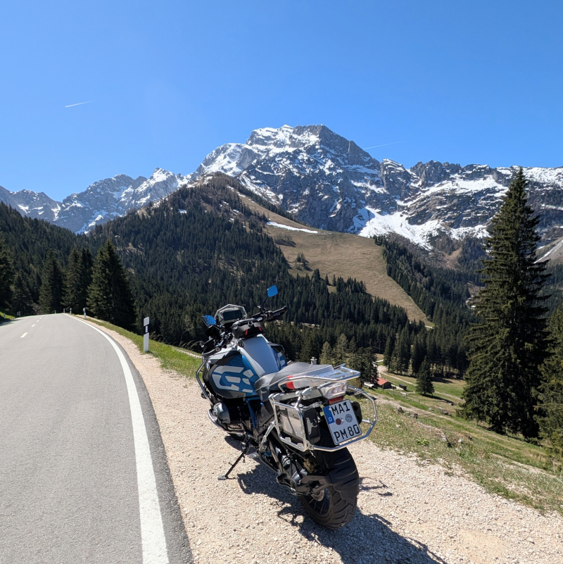 Fokus auf die BMW R1200GS Adventure am Streckenrand der Rossfeld Panoramastraße vor einem massiven Felsmassiv der Alpen.