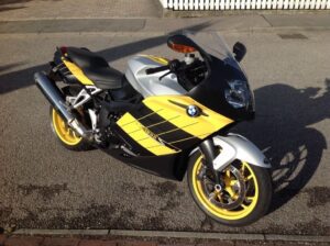 Gelb-schwarze BMW K 1200 S mit silbernen Akzenten auf grauem Asphalt; markante gelbe Felgen und "1200"-Schriftzug sichtbar.