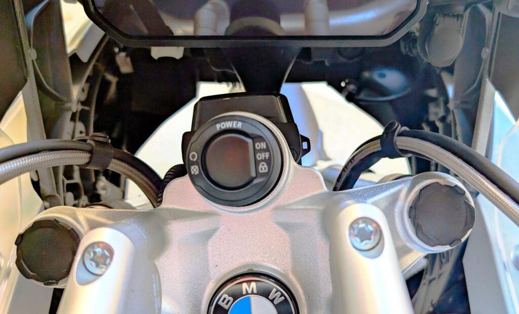 Silberne BMW Motorrad Gabelbrücke mit Power On/Off Schalter und zentralem BMW Logo.