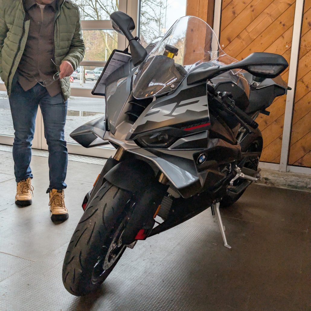 Grau-schwarzes BMW RR Sportmotorrad mit Kunststoffverkleidung parkt im Ausstellungsraum.