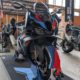 BMW M 1000 RR Motorrad in Schwarz mit M-Farben, Carbon-Winglets und Reifenwärmern auf einem Ausstellungsstand.