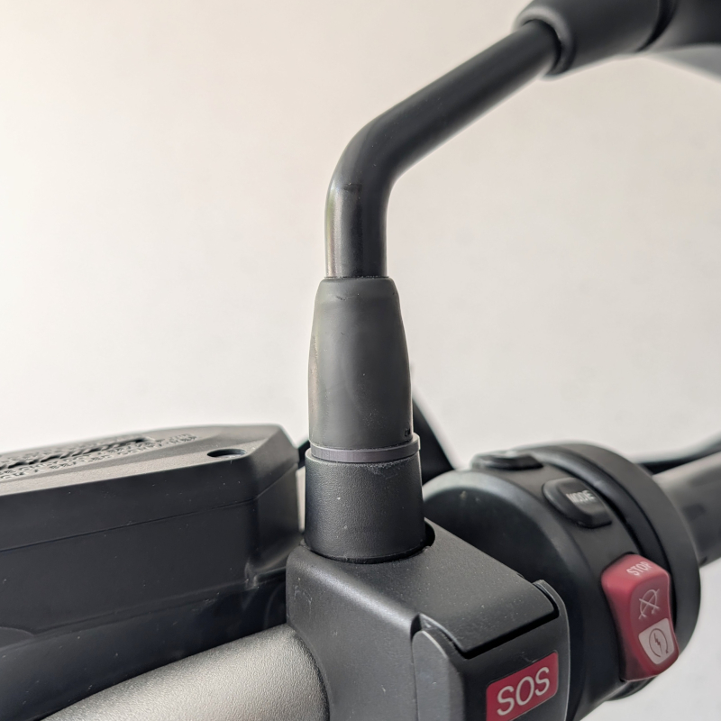 Detailaufnahme einer Motorrad-Armatur mit schwarzem Spiegelarm, SOS-Knopf und Bedienelementen aus Kunststoff.