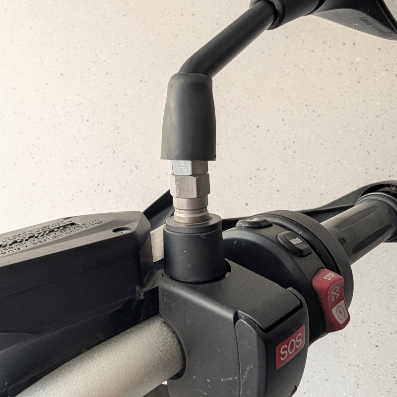 Detailaufnahme einer Motorrad-Armatur mit freiliegender Metallverschraubung am Spiegelarm und rotem SOS-Knopf.