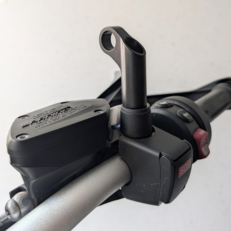 Schwarze Metall-Halterung montiert auf einer Motorrad-Armatur mit rotem SOS-Knopf und Bremsflüssigkeitsbehälter.