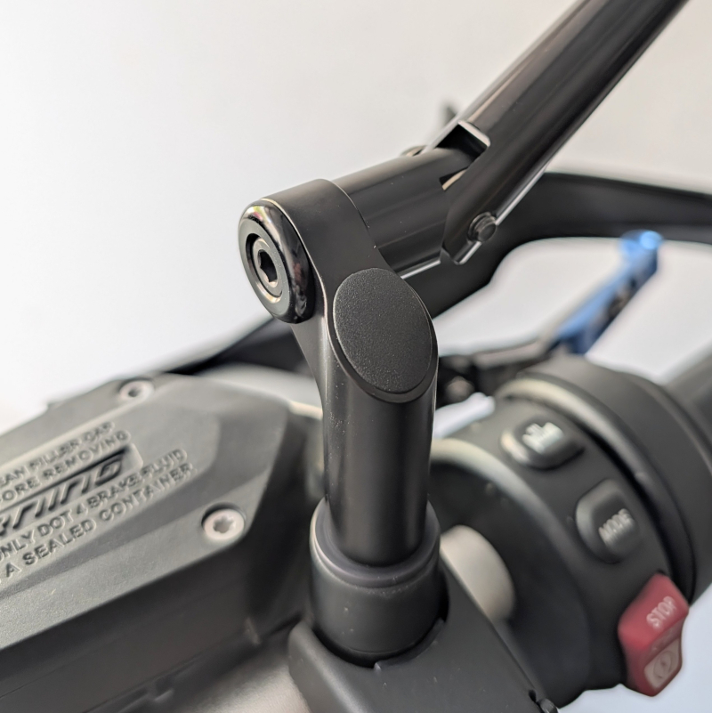 Inbusschraube fixiert schwarzen Metall-Spiegelarm auf Motorrad-Bedienelement, unscharfer Hintergrund.
