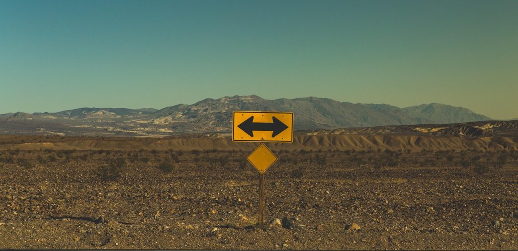 Gelbes Verkehrszeichen steht am Rand einer Straße in einer kargen Landschaft aus Sand und Steinen
