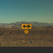 Gelbes Verkehrszeichen steht am Rand einer Straße in einer kargen Landschaft aus Sand und Steinen