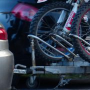 Silberner Motorradanhänger aus Metall, beladen mit zwei Motocross-Maschinen, angehängt an einen PKW.