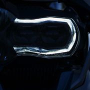 Nahaufnahme des leuchtenden, u-förmigen LED-Tagfahrlichts (BMW LED) eines Motorrad-Scheinwerfers bei Dunkelheit.